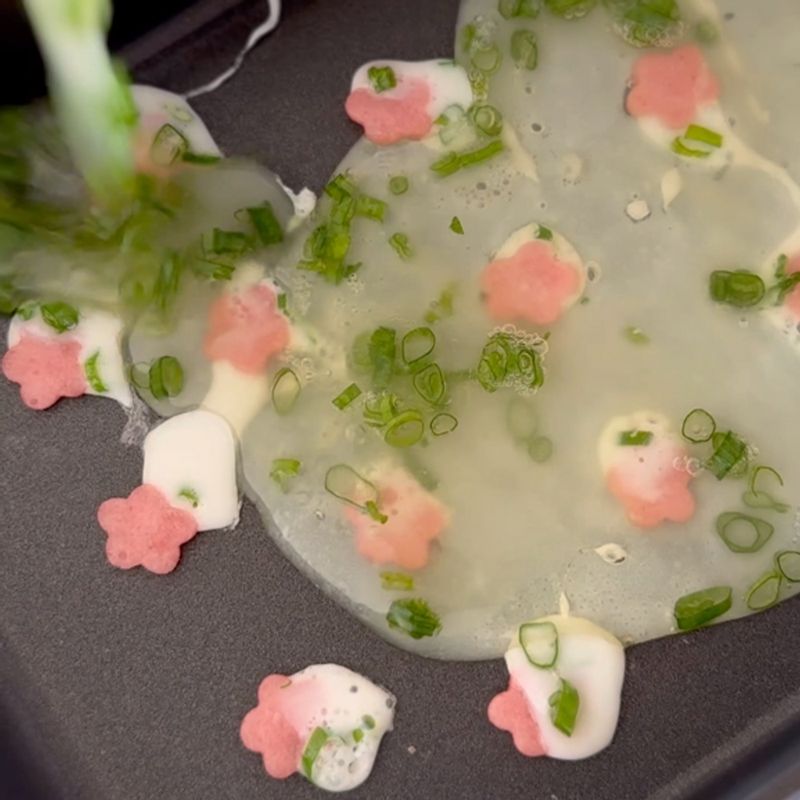 弱火で混ぜ合わせた卵白と万能ねぎをそっと流し入れます。半分に折りたたんで厚みを出せば、ベッドと枕の完成です！この工程をもう一度繰り返し、今度は折りたたまずに薄焼き卵を裏返してお布団を作ります。