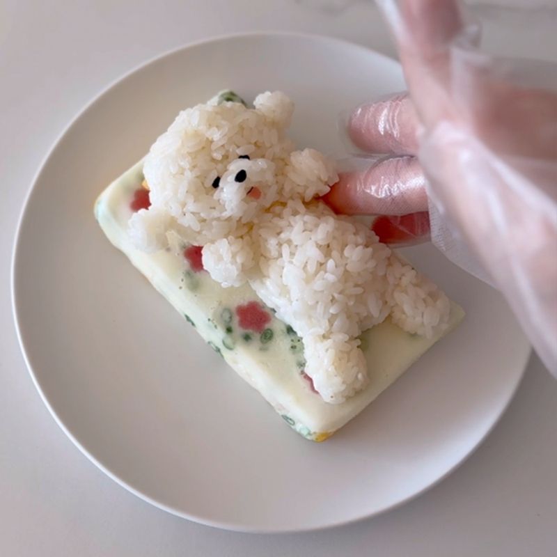 白ごはんに塩、ごま油で味付けをし、ビションフリーゼの頭と体の形を作ります。海苔をカットしてビションフリーゼの目、鼻、口を作り、頭と体を繋ぎ合わせます。